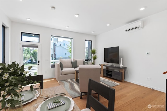 living room with plenty of natural light, light wood-type flooring, and an AC wall unit