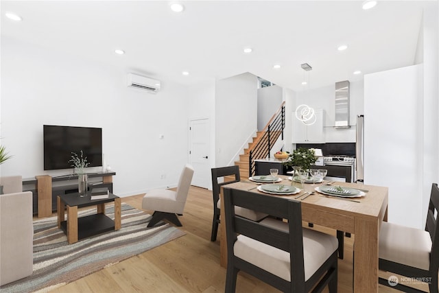 dining room with a wall mounted air conditioner and light wood-type flooring