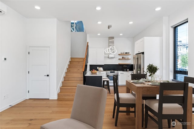 dining space with a wall mounted air conditioner and light wood-type flooring