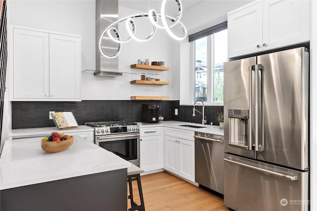 kitchen with sink, white cabinetry, high quality appliances, light stone countertops, and exhaust hood