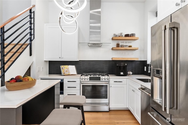 kitchen with range hood, stainless steel appliances, light hardwood / wood-style floors, white cabinets, and decorative backsplash