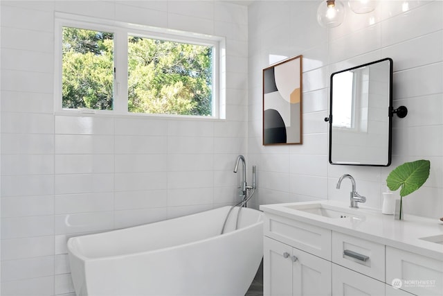 bathroom with vanity, a tub, and tile walls