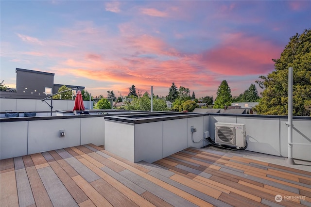 patio terrace at dusk featuring a balcony and ac unit