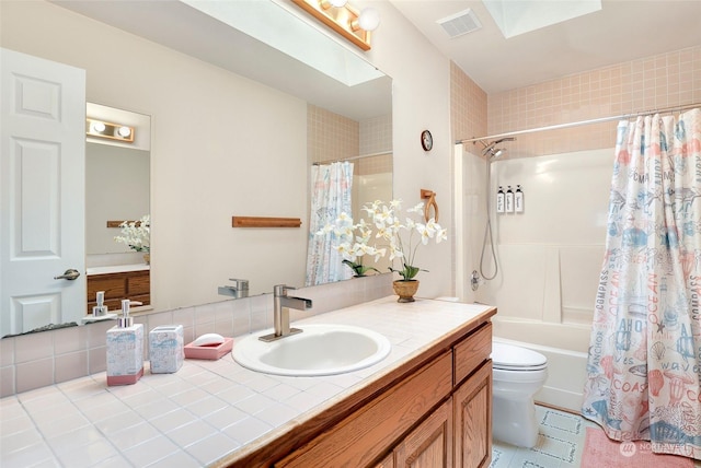 bathroom featuring a skylight, shower / tub combo with curtain, visible vents, toilet, and vanity