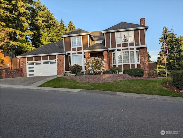 view of front of property with driveway, brick siding, a chimney, an attached garage, and a front yard