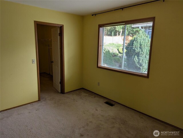 spare room with baseboards, visible vents, and light colored carpet