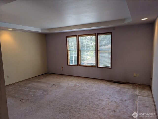 spare room with carpet floors, a tray ceiling, and recessed lighting