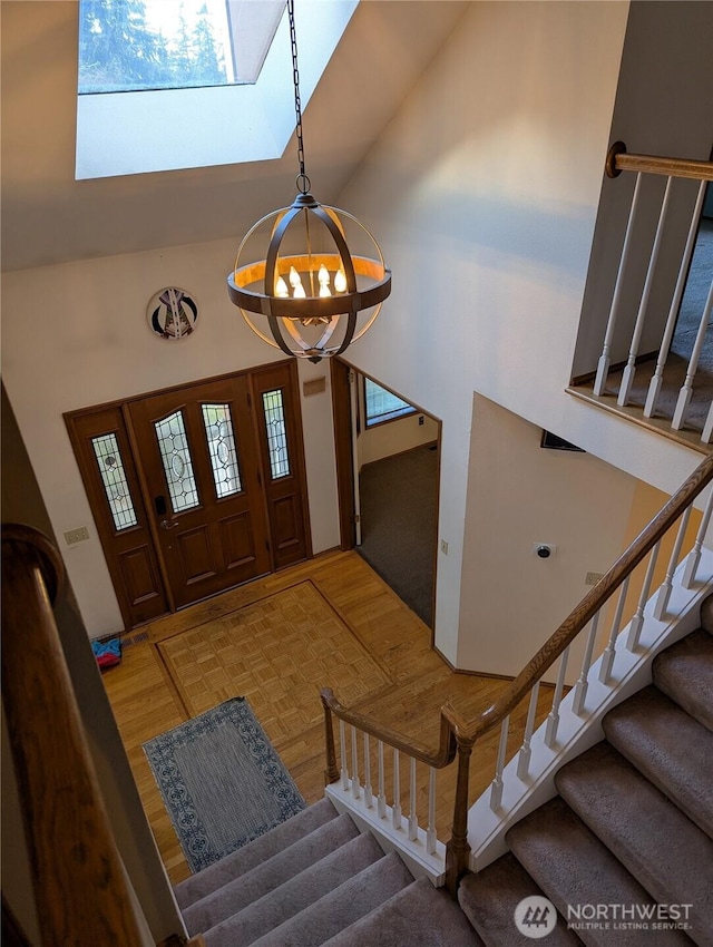 foyer entrance featuring stairs, high vaulted ceiling, light wood-type flooring, and a chandelier