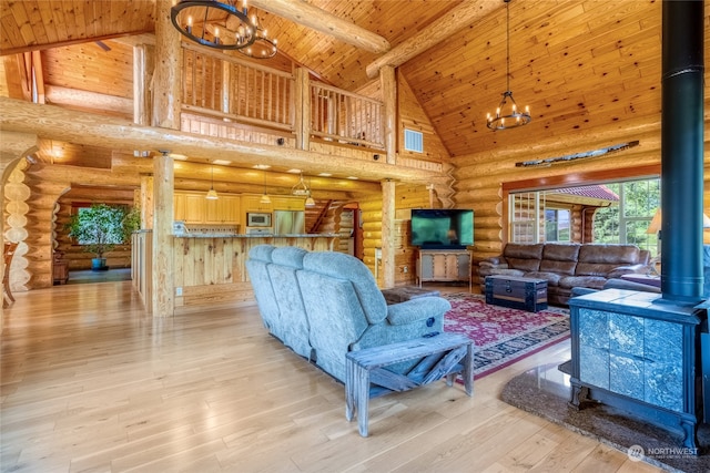 living room with high vaulted ceiling, a wood stove, light wood-type flooring, wood ceiling, and an inviting chandelier