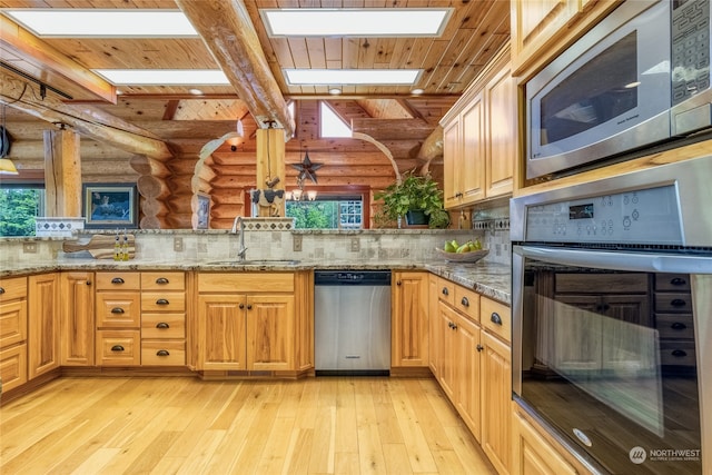 kitchen featuring tasteful backsplash, sink, light stone countertops, and appliances with stainless steel finishes