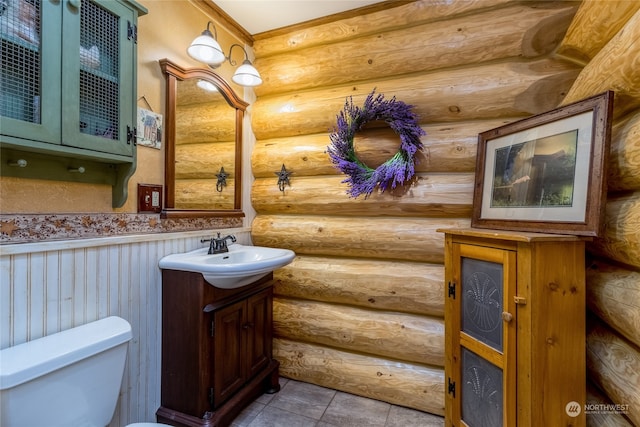 bathroom with tile patterned flooring, vanity, log walls, and toilet