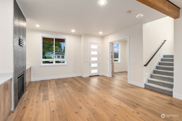 entrance foyer featuring a fireplace, beamed ceiling, and light hardwood / wood-style floors