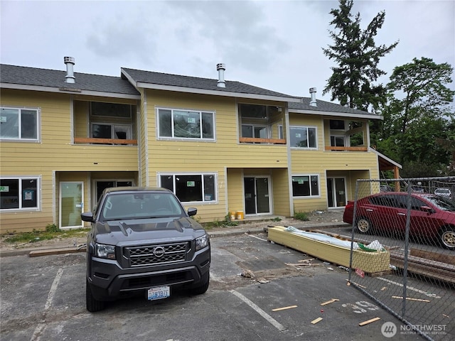 view of building exterior featuring uncovered parking and fence