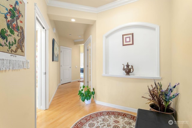 hallway with light wood-type flooring and crown molding