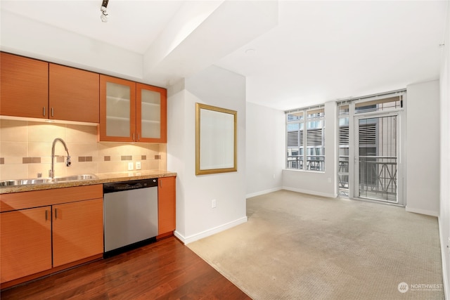 kitchen featuring carpet, tasteful backsplash, light stone countertops, stainless steel dishwasher, and sink