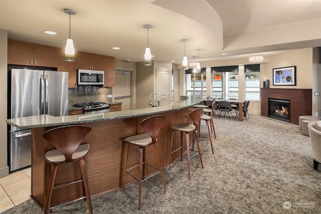 kitchen featuring dark stone counters, a breakfast bar, pendant lighting, and appliances with stainless steel finishes