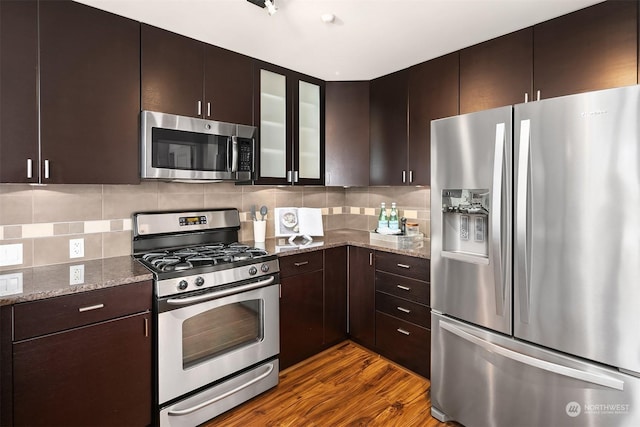 kitchen with light stone counters, dark brown cabinetry, dark wood-type flooring, and appliances with stainless steel finishes