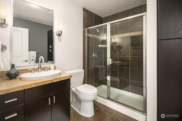 bathroom with tile patterned flooring, vanity, an enclosed shower, and toilet