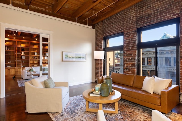 living room with wooden ceiling, a towering ceiling, beam ceiling, dark hardwood / wood-style flooring, and brick wall