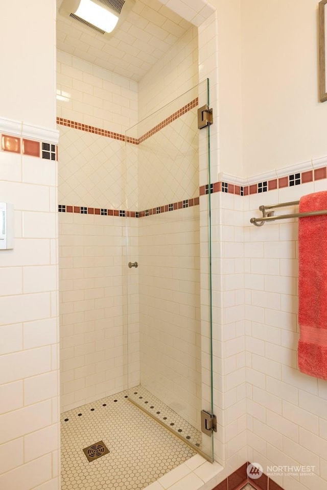 bathroom featuring tiled shower and tile walls