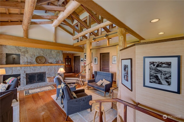 living room with beam ceiling, a stone fireplace, light hardwood / wood-style flooring, and high vaulted ceiling