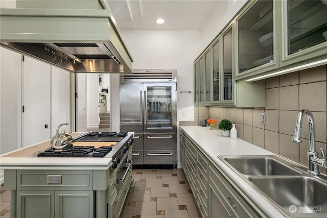 kitchen featuring sink, a center island, built in fridge, decorative backsplash, and green cabinetry