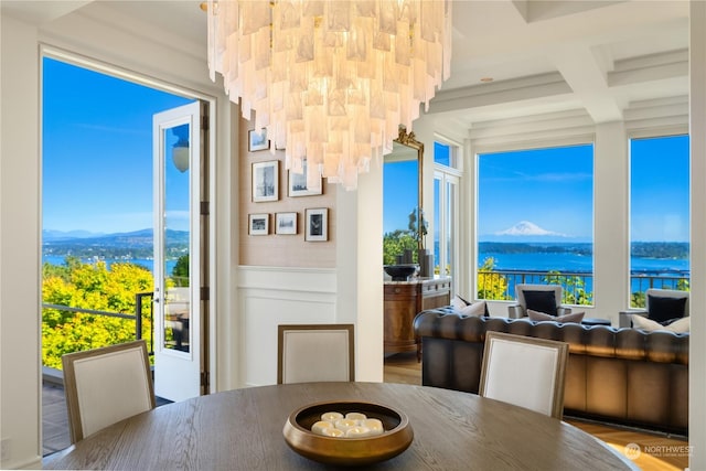 dining space featuring hardwood / wood-style flooring, a healthy amount of sunlight, beamed ceiling, and a water and mountain view