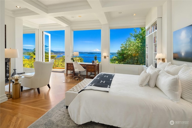 bedroom featuring beamed ceiling, a water view, a high end fireplace, and light parquet flooring