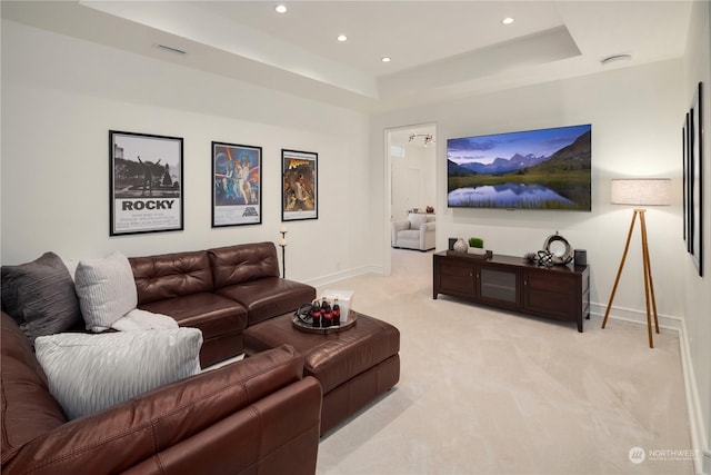 living room with a raised ceiling and light colored carpet