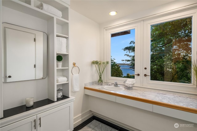 bathroom with tile patterned flooring, vanity, a water view, and a wealth of natural light