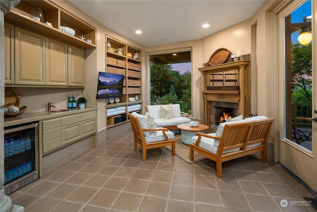 living area featuring built in shelves, wine cooler, bar area, a fireplace, and light tile patterned floors