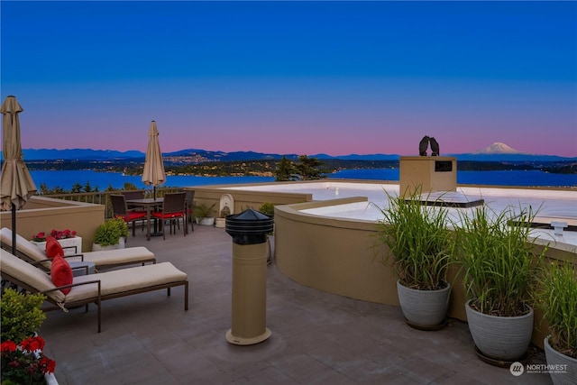 patio terrace at dusk with a water and mountain view