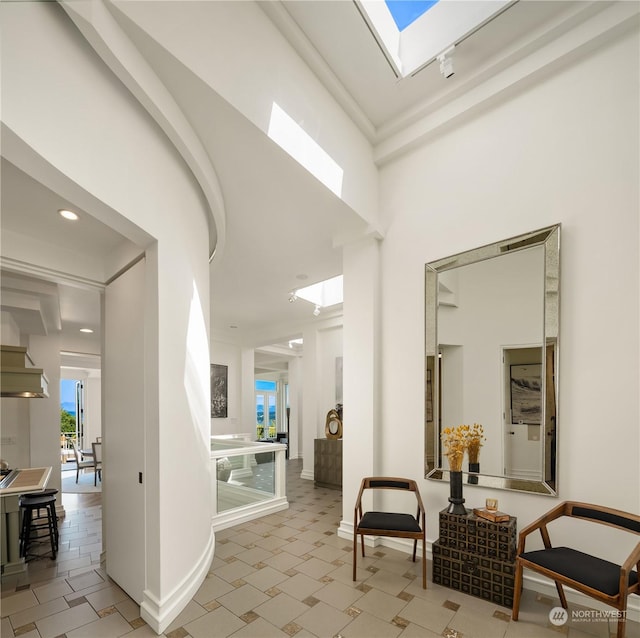 corridor with a towering ceiling and a skylight