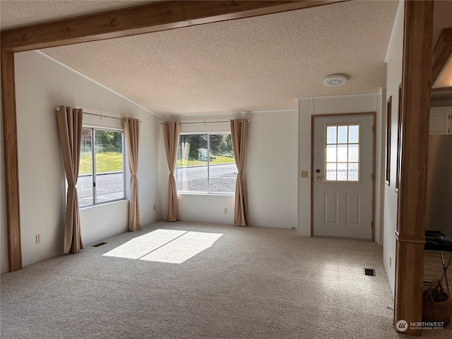 interior space featuring light colored carpet, lofted ceiling with beams, and a textured ceiling