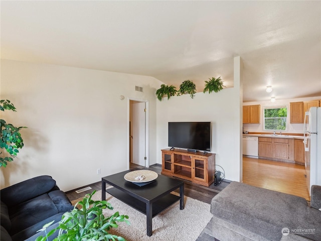 living room featuring sink, vaulted ceiling, and light hardwood / wood-style flooring