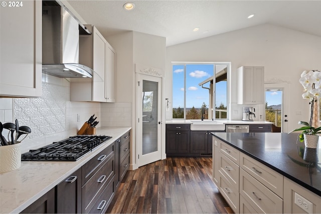 kitchen with lofted ceiling, sink, backsplash, and wall chimney exhaust hood