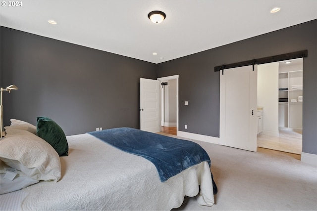 bedroom with carpet floors, a barn door, and a spacious closet