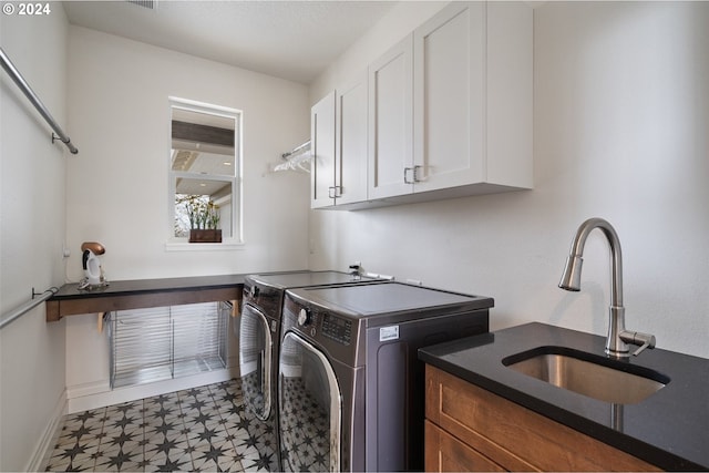 clothes washing area with cabinets, sink, and washer and clothes dryer