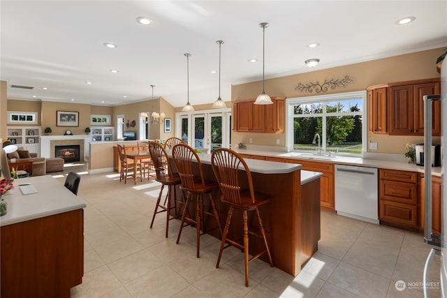 kitchen with stainless steel dishwasher, hanging light fixtures, sink, a kitchen island, and light tile patterned floors