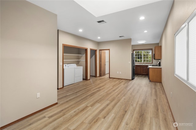 unfurnished bedroom featuring stainless steel refrigerator, washing machine and dryer, and light wood-type flooring