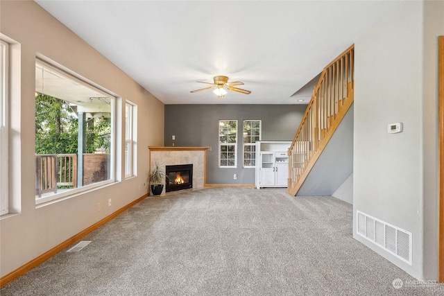 unfurnished living room featuring ceiling fan, carpet floors, and a fireplace