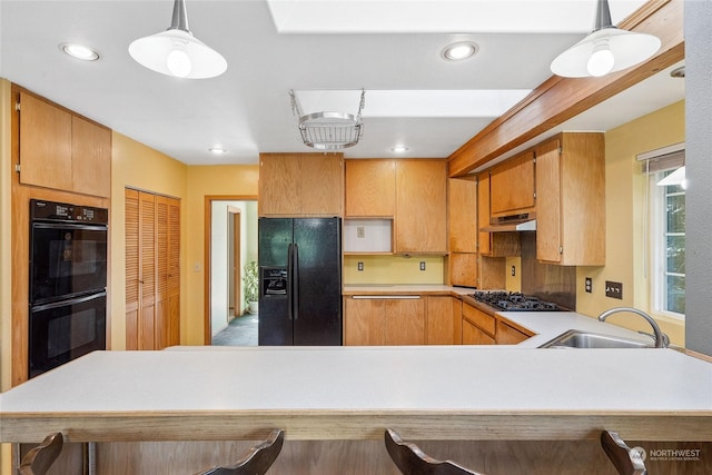 kitchen featuring sink, a kitchen breakfast bar, kitchen peninsula, decorative light fixtures, and black appliances