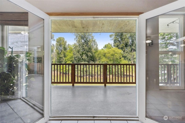 doorway to outside featuring tile patterned flooring, a healthy amount of sunlight, and a water view