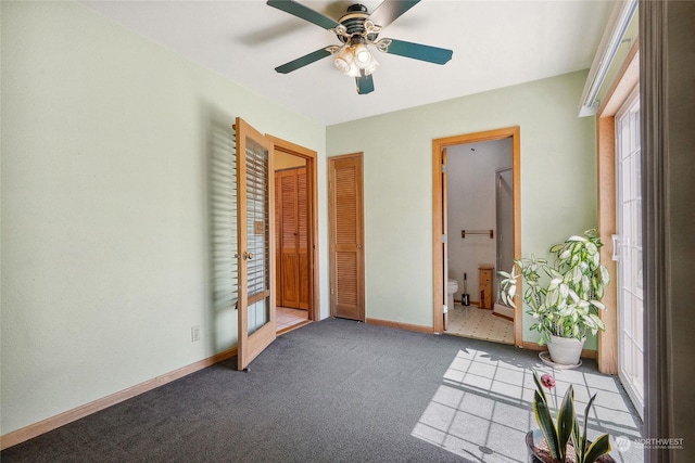 interior space featuring french doors, connected bathroom, light colored carpet, and ceiling fan