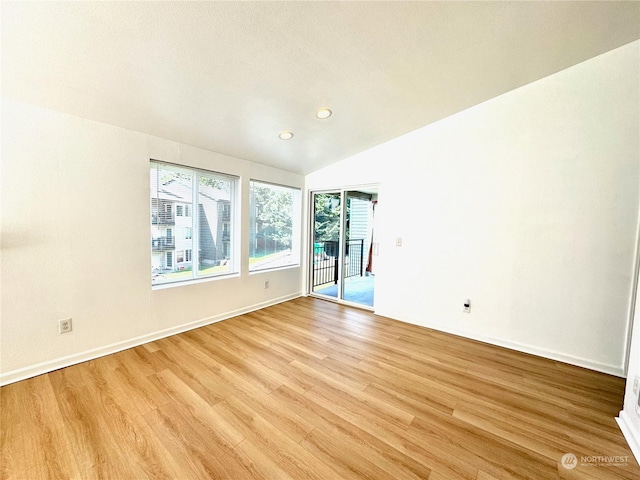 empty room featuring vaulted ceiling and light hardwood / wood-style flooring