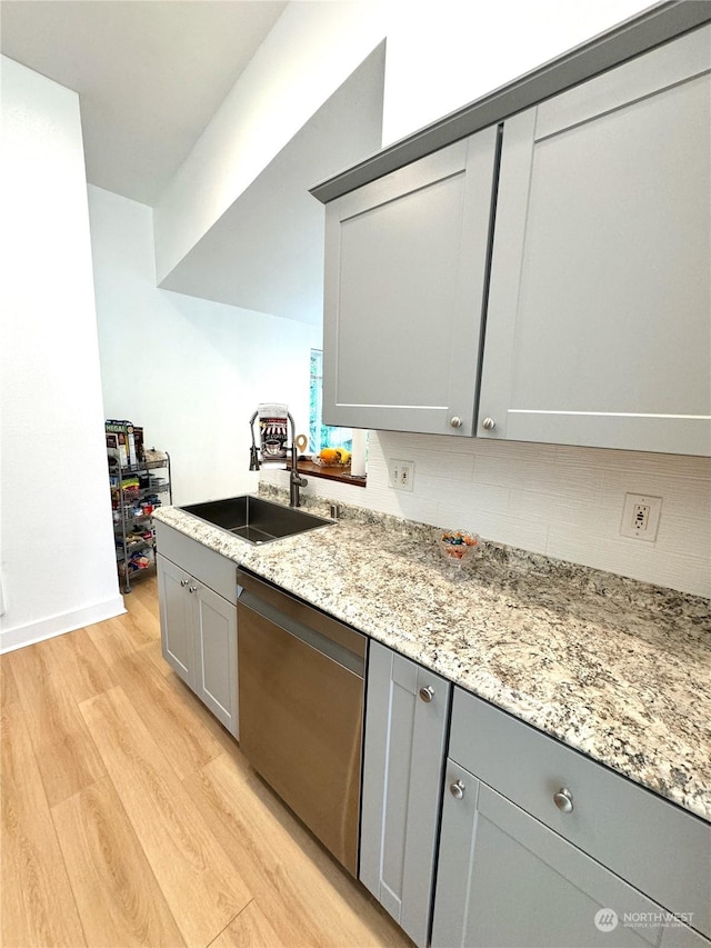 kitchen featuring sink, dishwasher, gray cabinetry, light stone counters, and light hardwood / wood-style floors