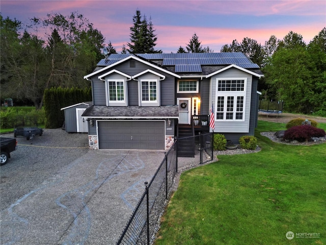 raised ranch featuring solar panels, a trampoline, a shed, a yard, and a garage