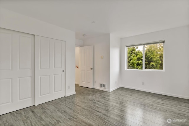 unfurnished bedroom featuring wood-type flooring and a closet