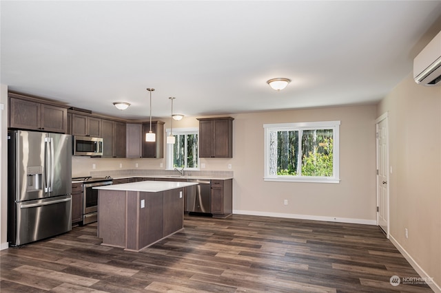 kitchen featuring dark hardwood / wood-style floors, pendant lighting, a wall unit AC, a kitchen island, and appliances with stainless steel finishes