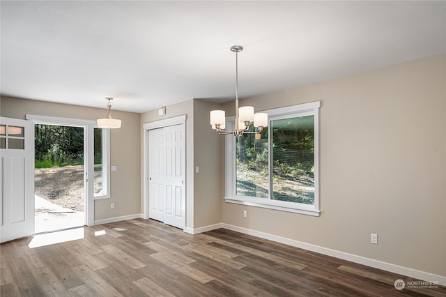 unfurnished dining area featuring dark hardwood / wood-style floors, plenty of natural light, and a notable chandelier